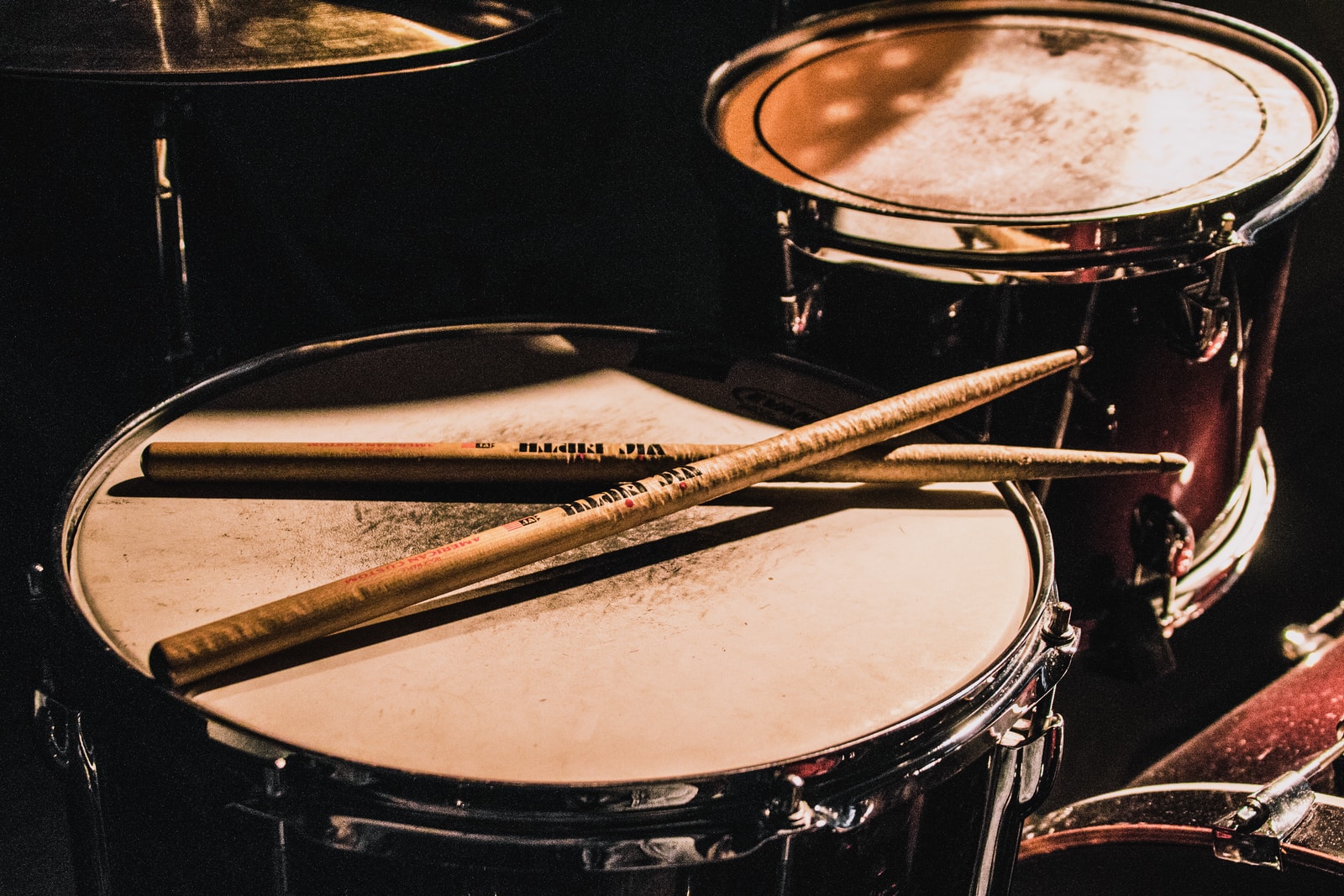 pair of brown wooden drumsticks on top of white and gray musical drum
